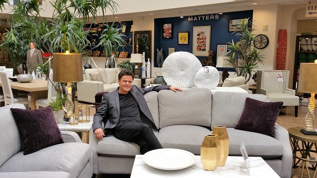 Donny Osmond sitting on his couch at Walker Furniture
